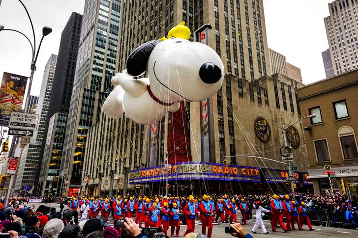 Snoopy balloon floats in the air during the annual Macy's Thanksgiving Day parade along Avenue of Americas with the Radio Music Hall in the background, 2014.